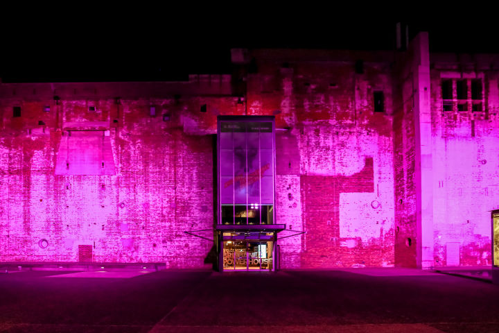 Brisbane Powerhouse's brick exterior wall lit up pink for Brisbane Festival.